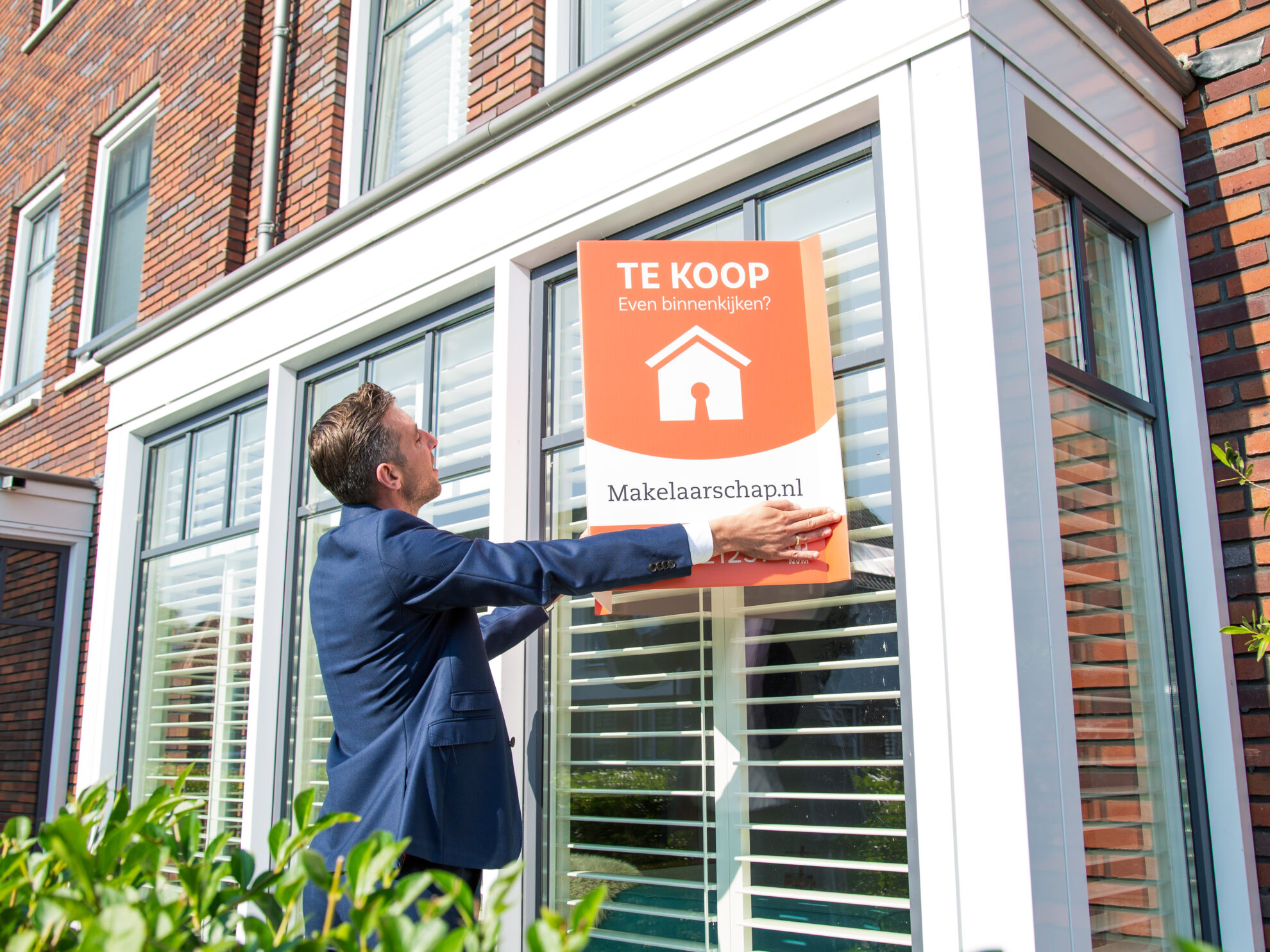 Man hangt een te koop bord op