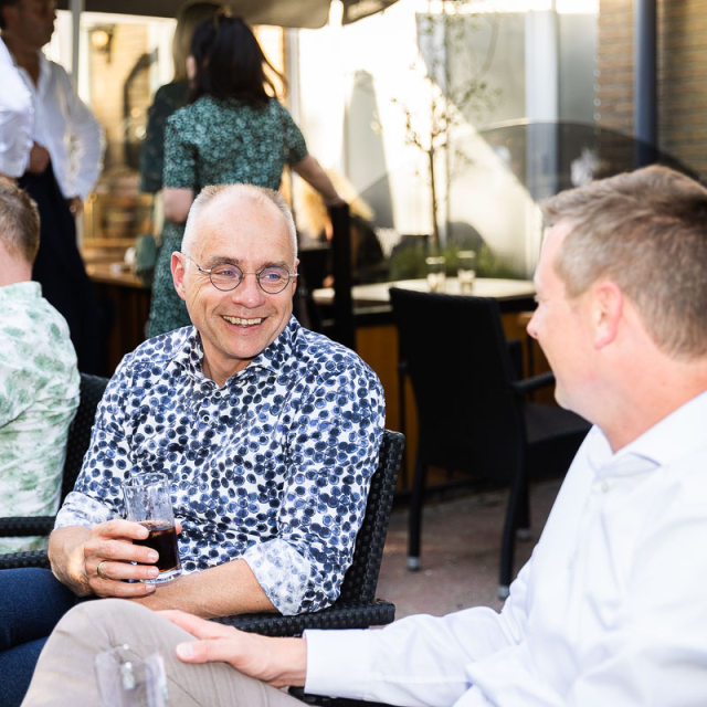 Mannen zitten en zijn met elkaar in gesprek en lachen.