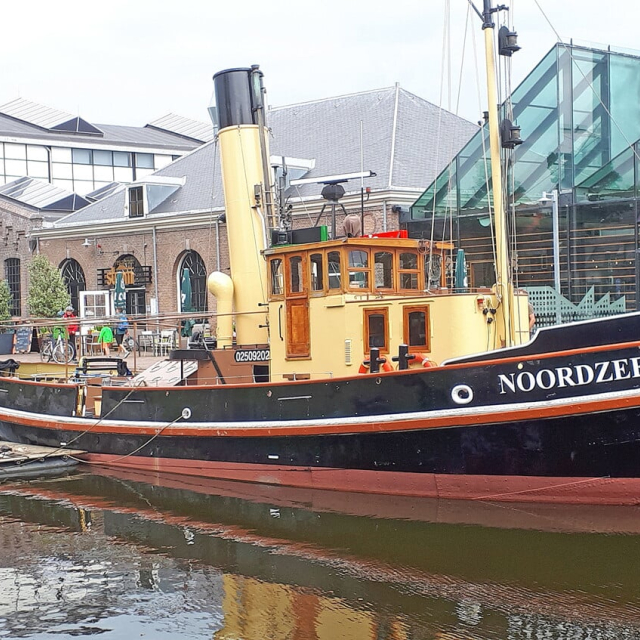 Boot aangemeerd aan een kade waar gebouwen staan