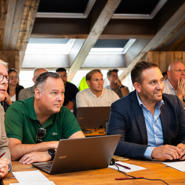 Mensen zitten in een zaal en luisteren naar een presentatie