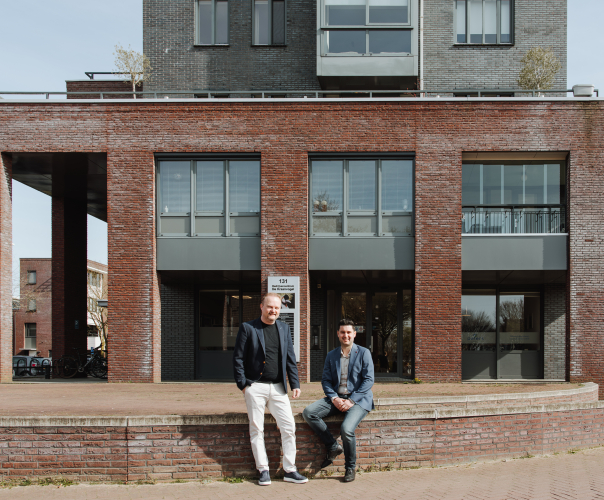 Twee mannen staan voor een gebouw